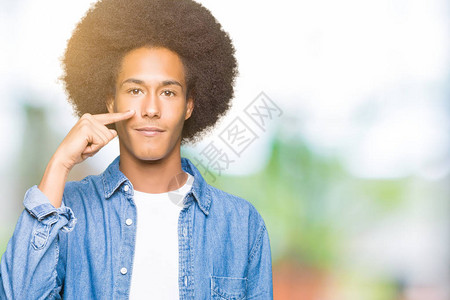 年轻的非洲美国人头发长着ffro的美男子用手指向脸和鼻子图片