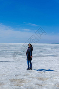 女孩走在冰海和蓝天空的背景上图片