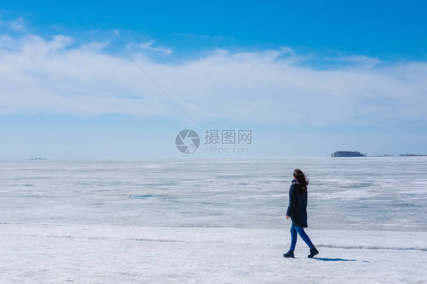 女孩走在冰海和蓝天的背景上冬天春图片