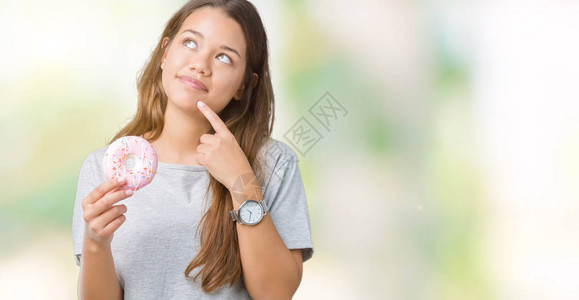 年轻漂亮的女人在孤立的背景下吃粉色甜圈图片