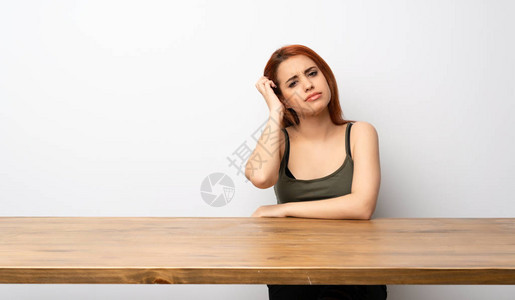 年轻的红发女青年在办公桌旁表现出沮丧和图片
