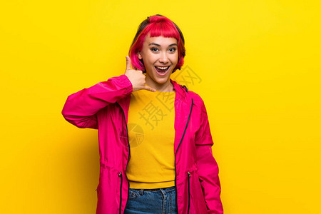 黄墙上有粉色头发的年轻女人做电话手图片