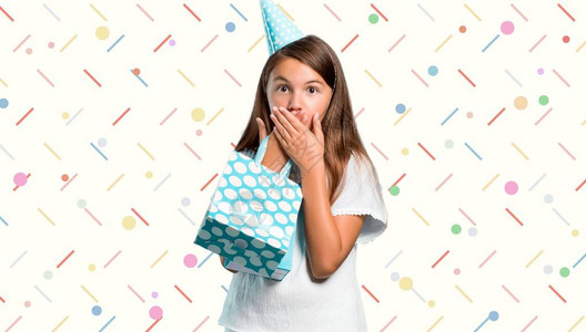 在生日派对上的小姑娘拿着一个礼物袋用彩色背景图片