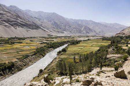 肥沃的瓦罕河谷与塔吉克斯坦弗朗附近的潘吉河背景中的山脉是阿富汗的图片