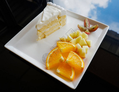 在白盘上切水果和牛奶蛋糕在托盘上特写新鲜橙葡萄和苹果片图片