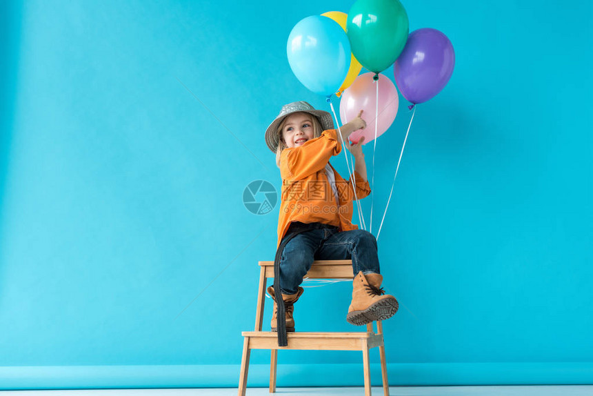 穿着牛仔裤和橙色衬衫的可爱孩子坐在楼梯上图片