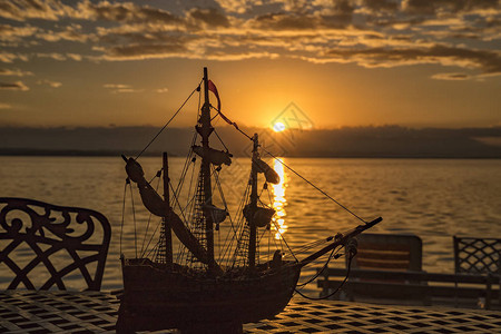 海边日出时一张桌边椅子和船玩图片