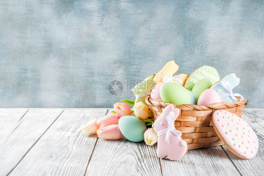 复活节贺卡背景与柔和的彩色鸡蛋和自制饼干形状的鸡蛋和兔子带篮子郁金香质朴的木图片