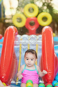 在儿童游泳池玩彩球的女婴图片