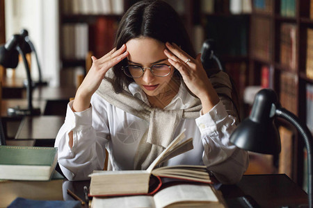 疲倦的学生女孩在考试前读了很多书图片