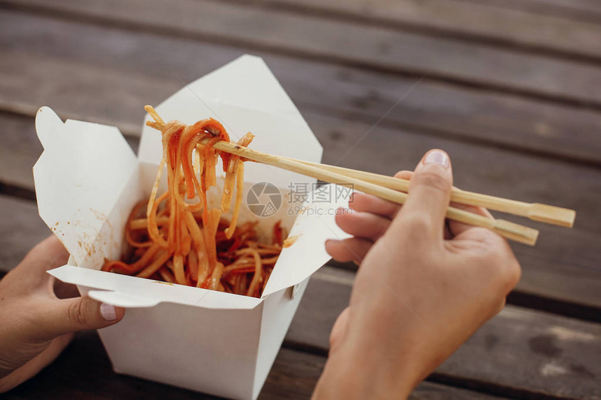 用纸箱里的面条和蔬菜和竹筷子一起炒锅传统的亚洲美食亚洲街头美食节女孩在开箱外卖中吃泰国图片