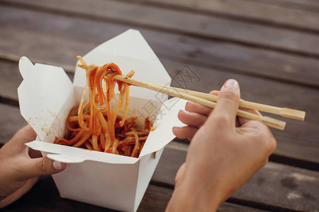 用纸箱里的面条和蔬菜和竹筷子一起炒锅传统的亚洲美食亚洲街头美食节女孩在开箱外卖中吃泰国背景图片