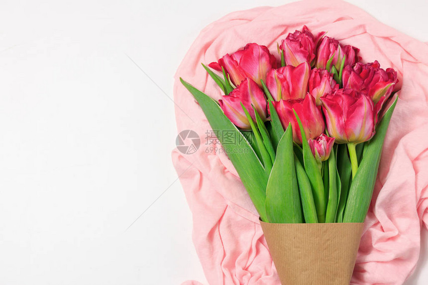 浅粉色布上的红色和粉色郁金香春天花束带有文本空间的图片