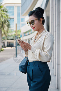 身着优雅衣服和墨镜手袋和手机的华丽亚洲女图片