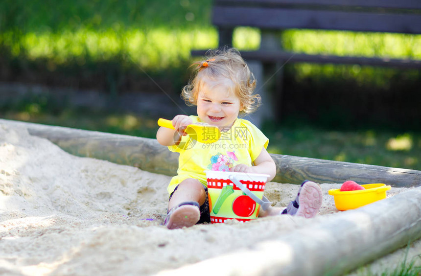 可爱的蹒跚学步的女孩在户外操场上的沙子里玩耍美丽的宝在阳光明媚的温暖夏日阳光明媚的日子里玩得开心快乐健康的孩子图片