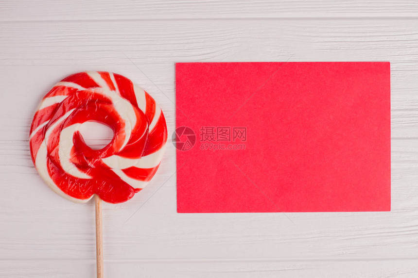 棒糖果和空白纸卡平铺红色纸片和螺旋棒糖在白色木制背景上孩子图片