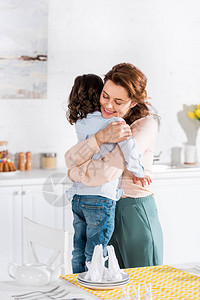 微笑的母亲抱着卷孩子在厨房旁边图片