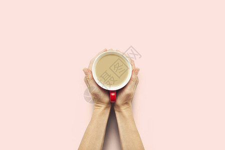 两只手拿着一杯粉红色背景的热咖啡早餐概念与咖啡或茶图片