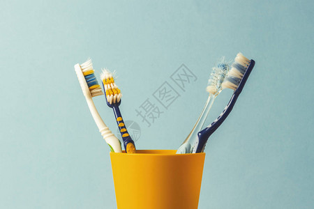 蓝色背景上塑料杯中的许多牙刷更换牙刷口腔卫生牙科的概念大图片