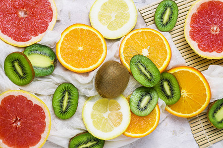 新鲜热带水果葡萄果柠檬橙子浅石背景的基维图片