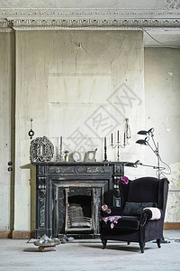 带扶手椅的旧黑色壁炉装饰前白墙图片