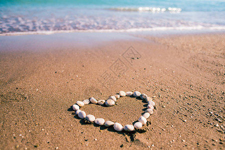 沙子上的鹅卵石之心爱的宣言情人节海水和沙子在沙滩上放松由石头制图片