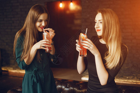 两个美丽的年轻和优雅女孩站在餐厅喝鸡尾酒图片