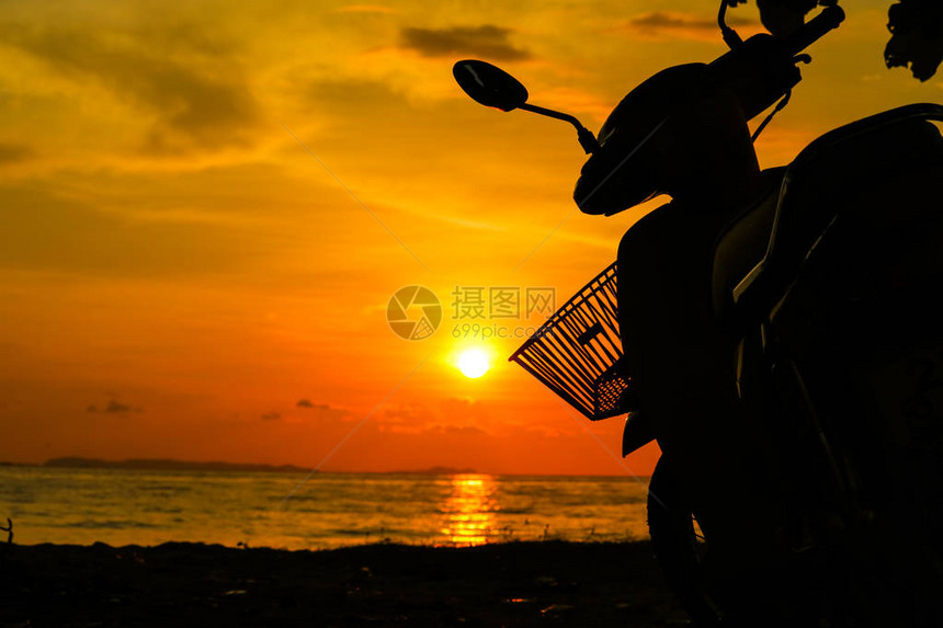 摩托车上的剪影篮和海上背景的日落图片