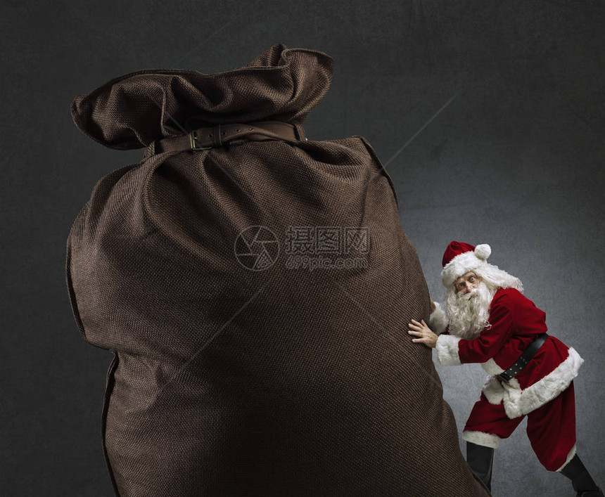 有趣的圣诞老人为孩子们送来一个沉重的大袋子图片