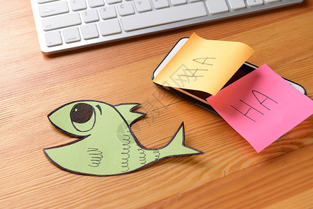 手机纸鱼和木头背景的粘贴笔记四月背景图片