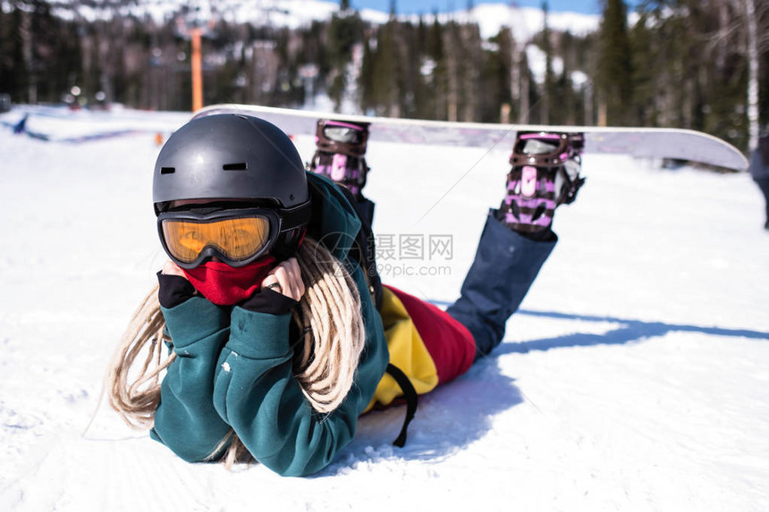 女滑雪者躺在雪坡上图片