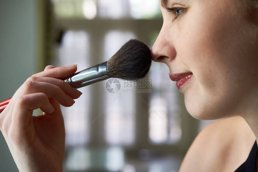 利用化妆刷子在脸上打干化妆用的年轻女图片
