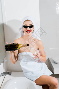 戴着太阳镜和毛巾的迷人微笑的女人在浴室里拿着图片