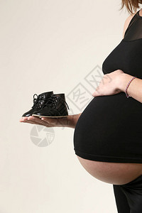 孕妇为她的孩子拿着鞋子图片