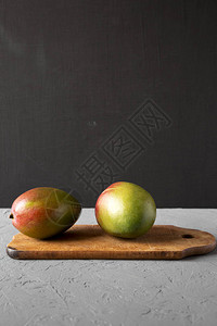 两只多彩甜蜜的芒果在生锈木板上侧图片