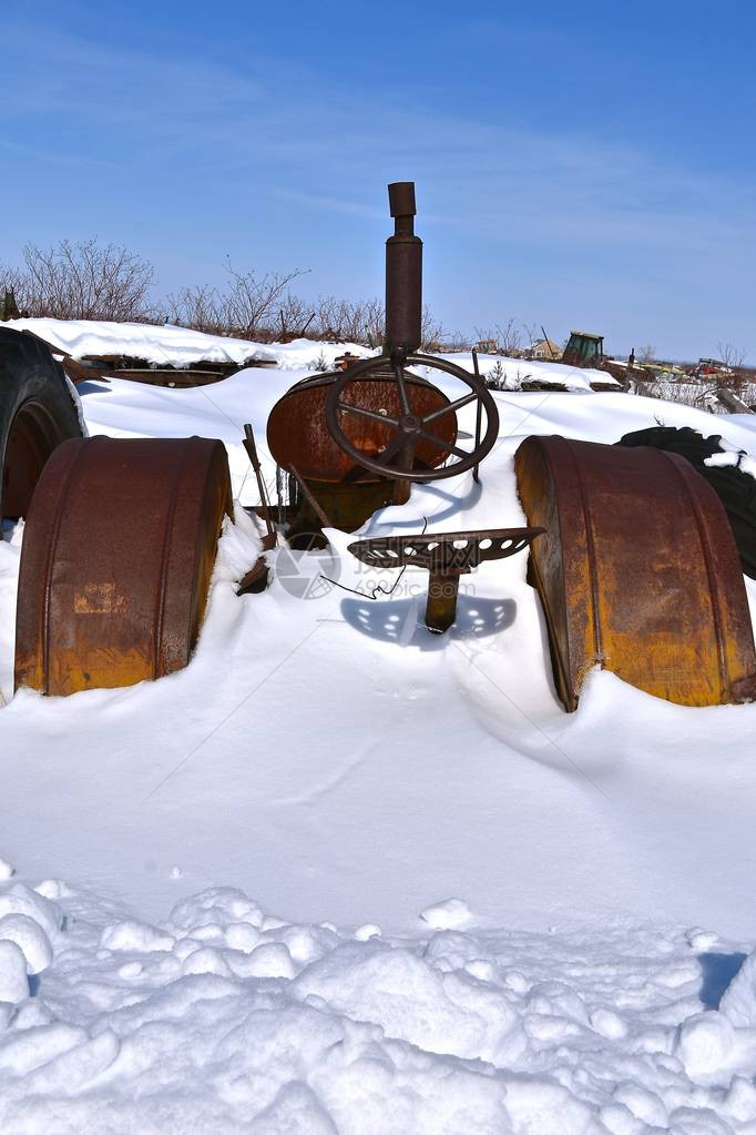 在暴风雪过后一辆旧的生锈拖拉机加上巨大的挡泥板被部图片