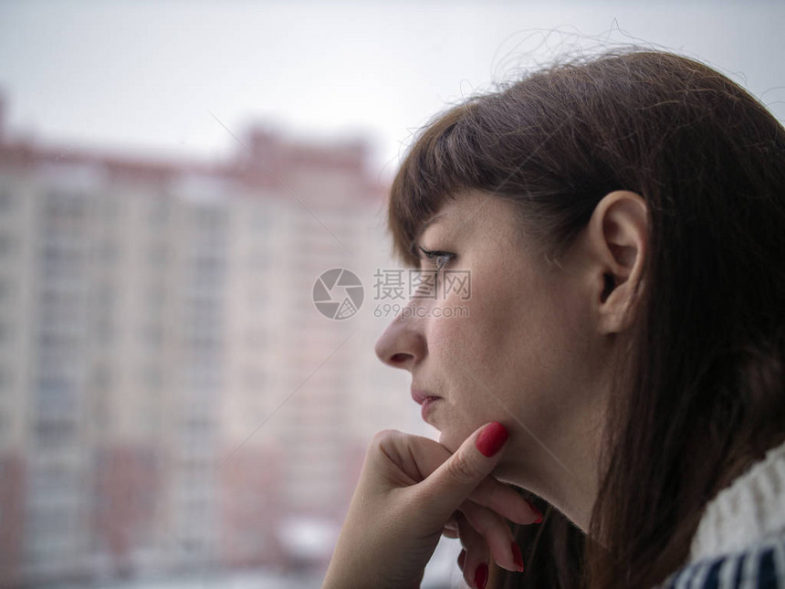 身长头发的年轻漂亮的黑发美女在房子背景下站在窗户近窗处时看上去很机灵地图片