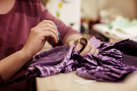女在裁缝工场用针头缝衣服背景图片