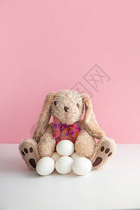 带鸡蛋白的软小兔子玩具在粉红背景图片