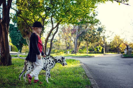 年轻女孩带着她的达马特犬在春天公园里图片