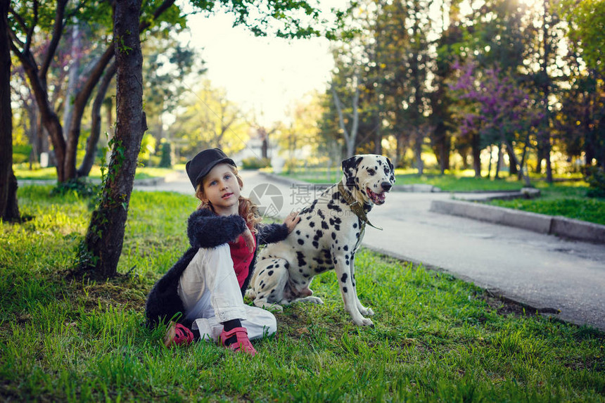 年轻女孩带着她的达马特犬在春天公园里图片