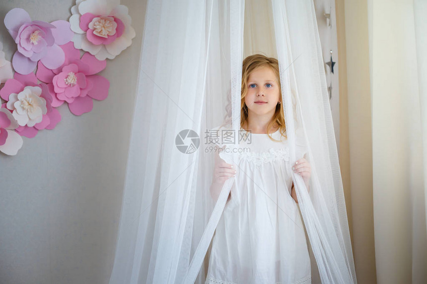 可爱的小女孩梦想成为公主带白色内衣鲜花和玩具的浅儿童房间图片
