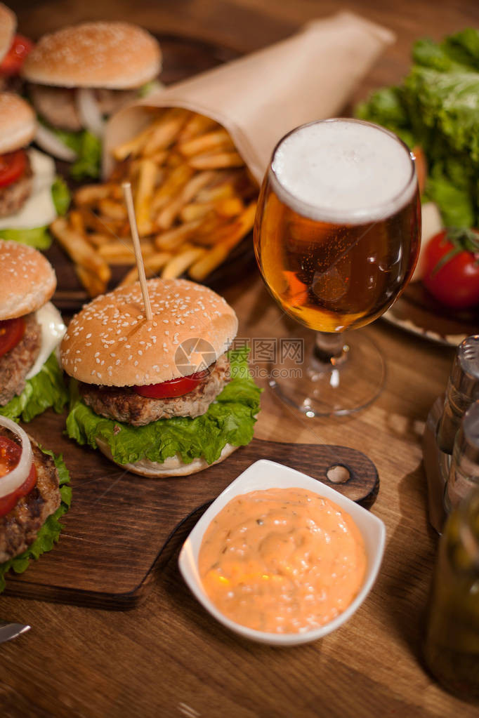 餐厅桌上的牛肉汉堡和啤酒美味的点心图片