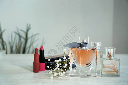 白桌上放着鲜花和化妆品的香水瓶图片