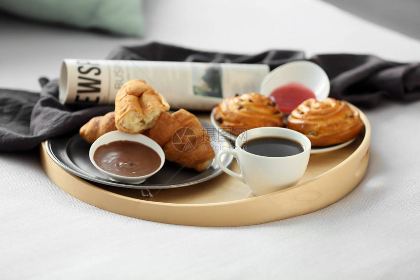 托盘上有美味的早餐和床上的报纸图片