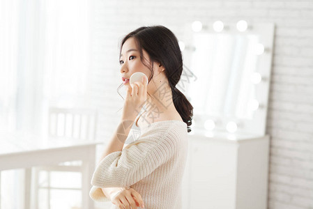 韩国年轻女子涂抹爽身粉的肖像图片