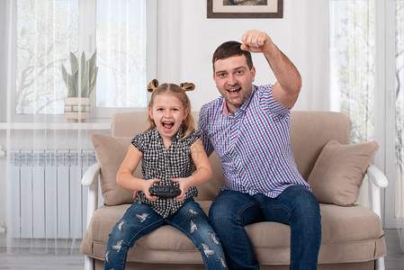 一个女儿和爸拿着操纵杆坐在家里的沙发上图片