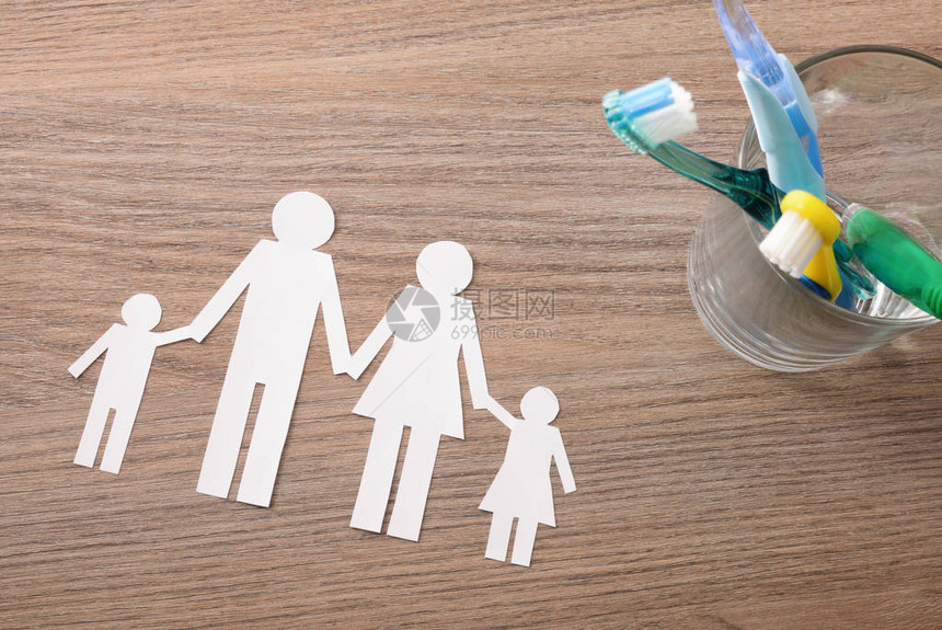整个家庭在家里用玻璃罐和牙刷以及木制桌子上的家庭切除物进行牙齿清洗的概念水平成份顶图片