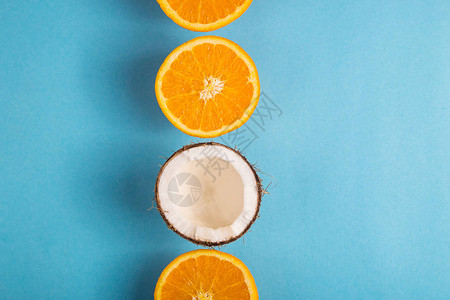 果汁成熟的橙子和开椰子在明蓝的色背景下夏季食品概念图片