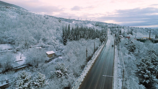 白雪皑的森林和在冬季道路上行驶的汽车的空中图片